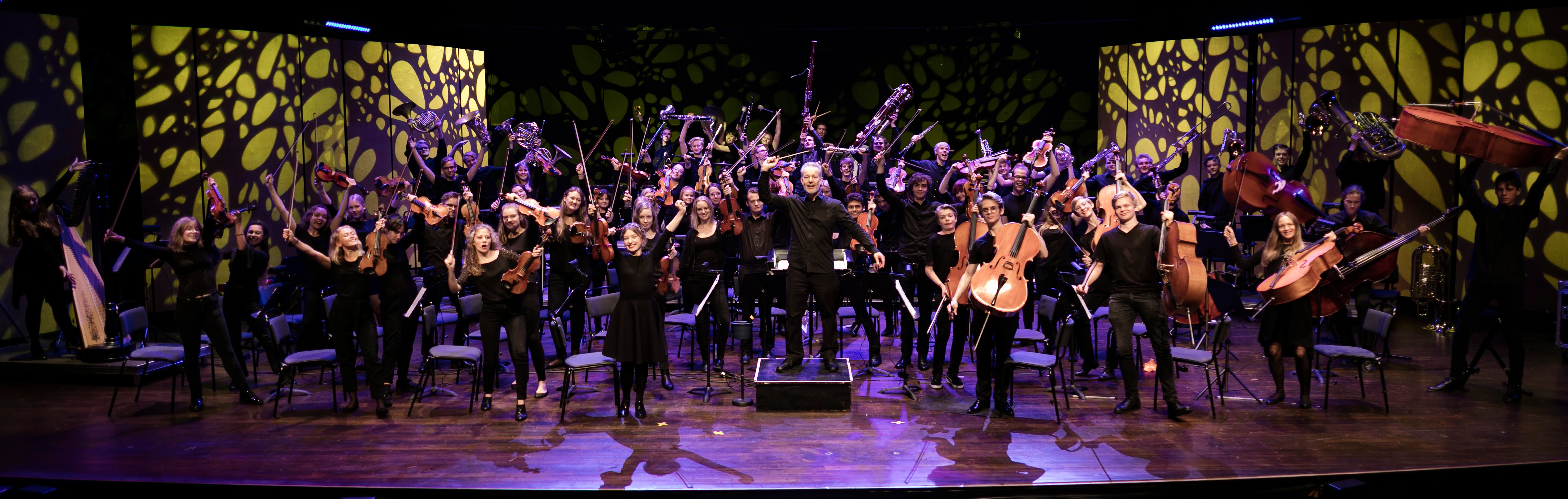 hela Vägus-orkestern poserar tillsammans med dirigenten simon phipps
