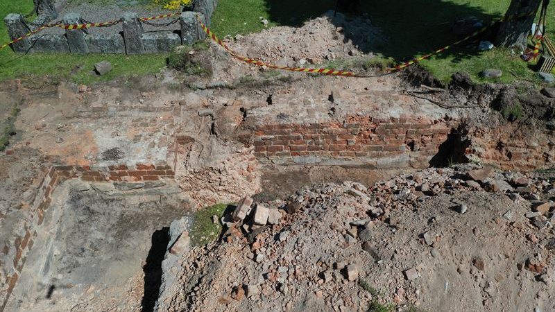 Bild på arkeologisk utgrävning. Grop med tegel murar som visar kyrkans korsarmar.