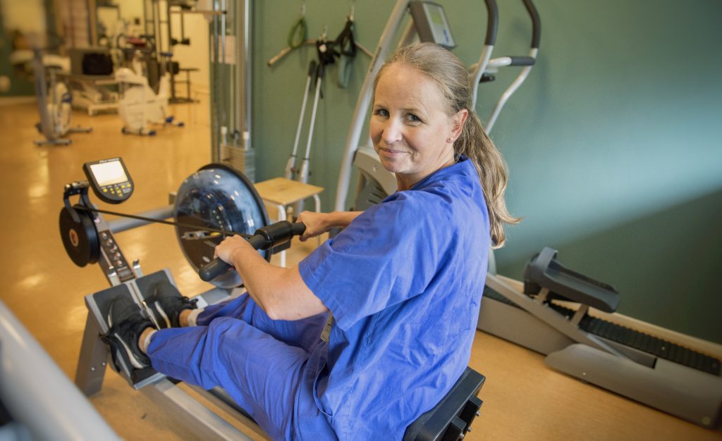 En kvinna sitter i en roddmaskin på ett gym