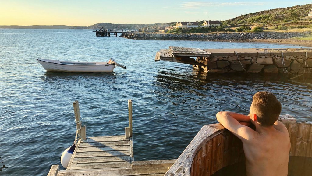 En man som badar badtunna blickar ut över havet och solnedgången.