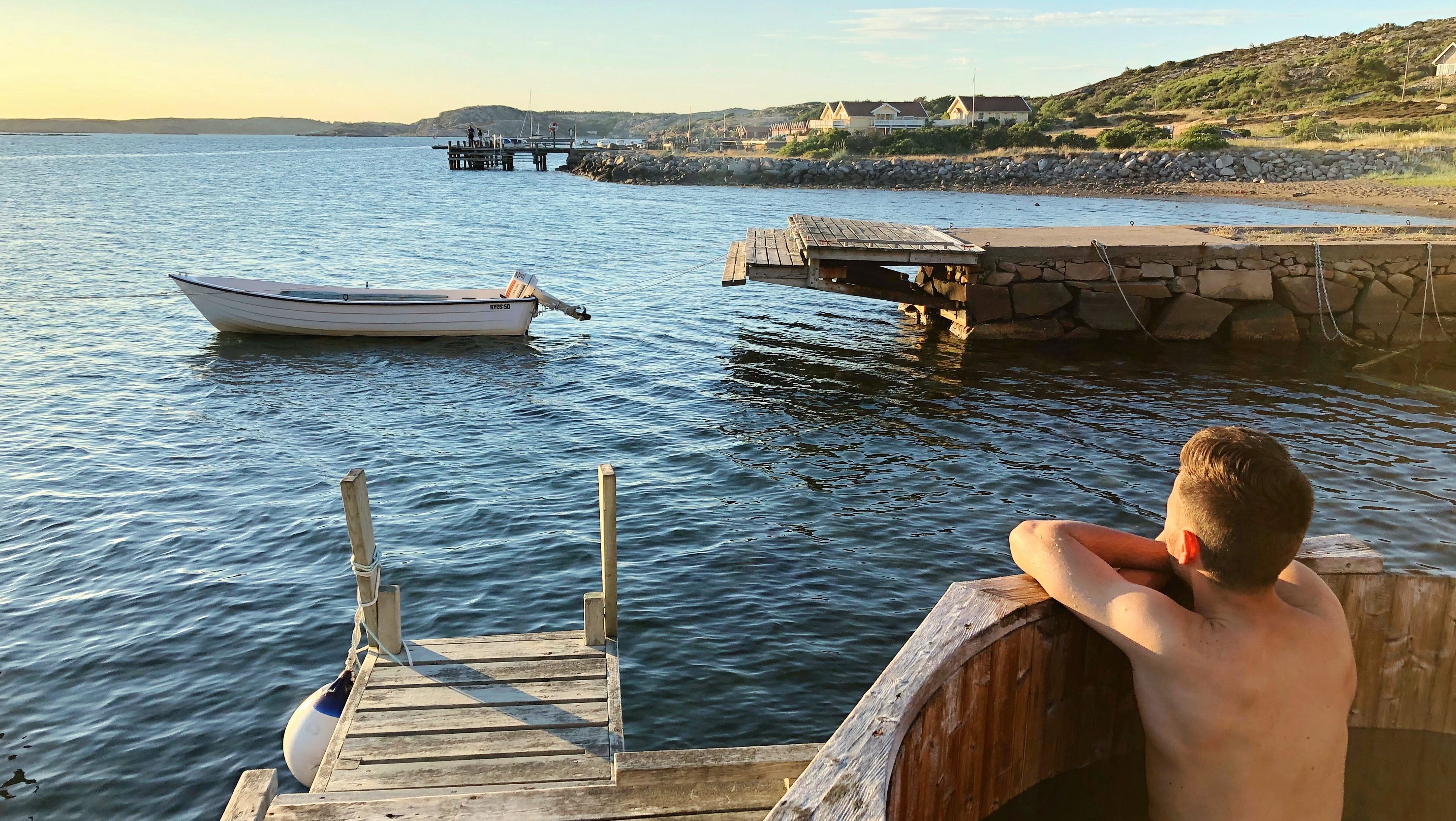 En man som badar badtunna blickar ut över havet och solnedgången.