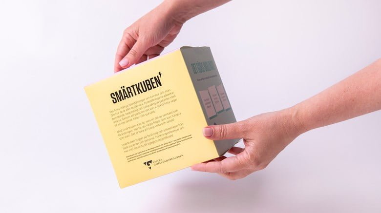 Bild på en fyrkantig papplåda med texten Smärtkub