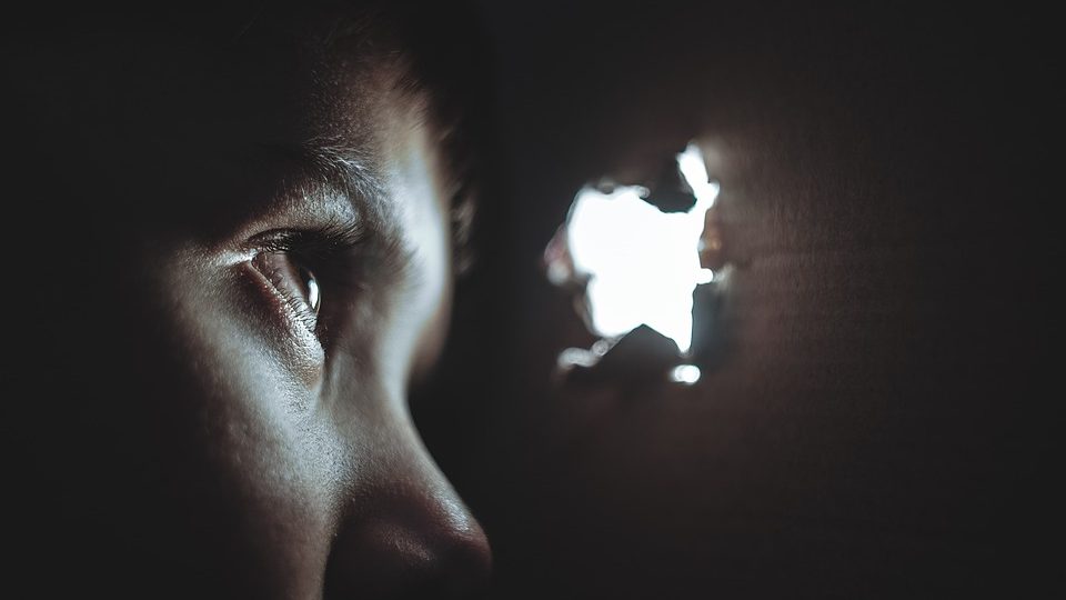 Bild på ett barn där man bara ser ögat som tittar ut genom ett hål i en kartong.