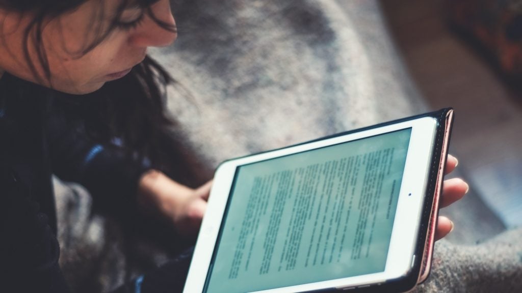 En person sitter och läser en text på en surfplatta