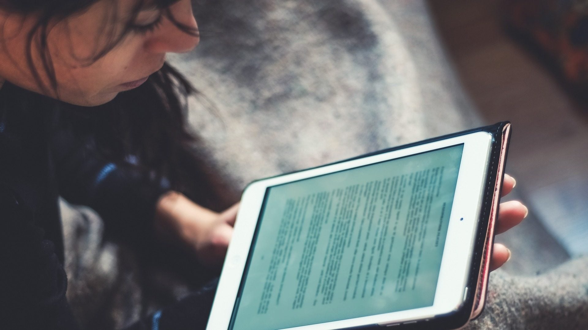 En person sitter och läser en text på en surfplatta