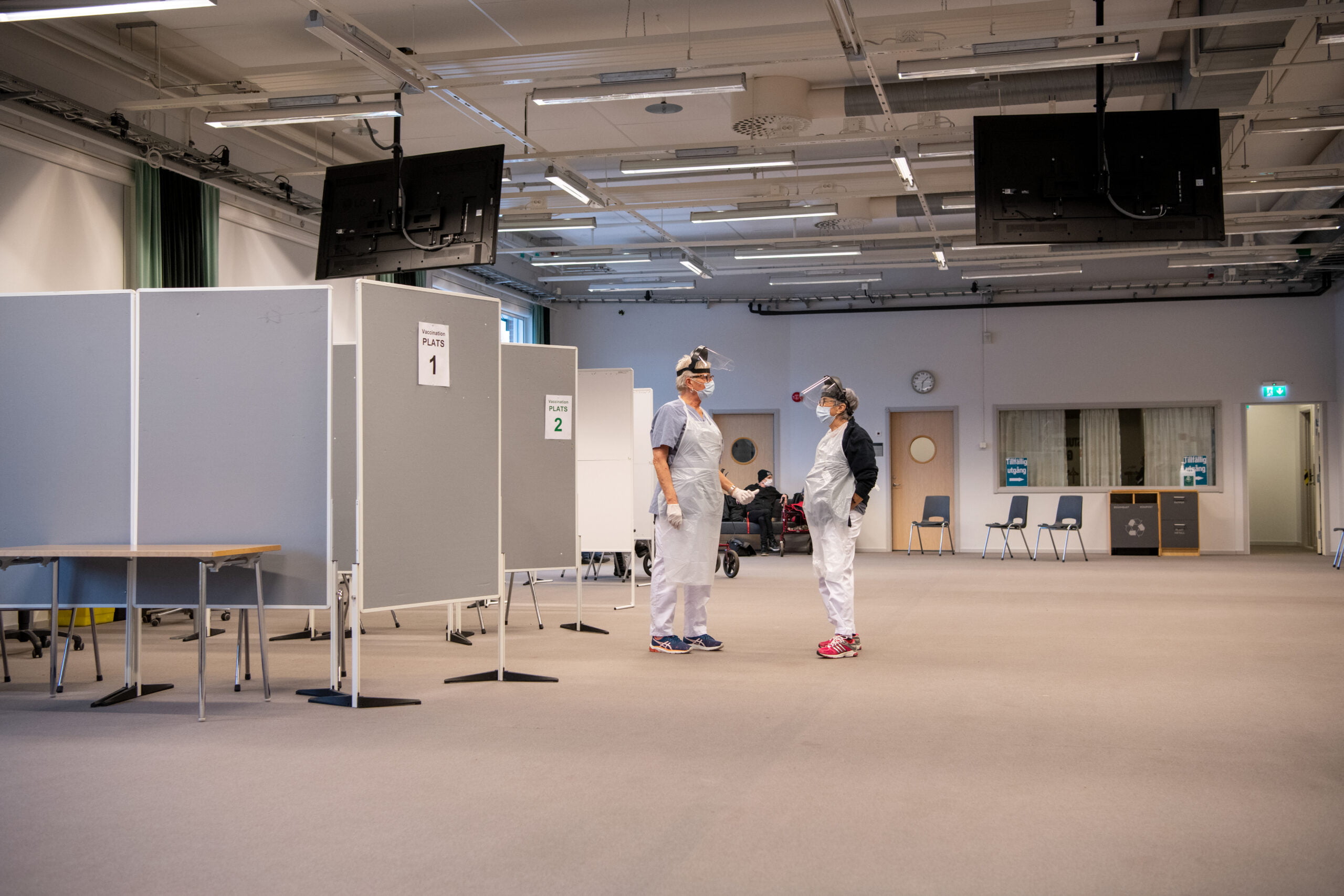 I lokalerna som Högskolan Väst lånar ut finns gott om plats så att vaccineringen kan flyta på både smidigt och smittsäkert.<br /> De vaccinerande sjuksköterskorna Birgitta Bondeson och Viola Svensson väntar på fler patienter. I bakgrunden syns efterväntrummet innanför den tillfälliga utgången. Foto: Kent Eng.
