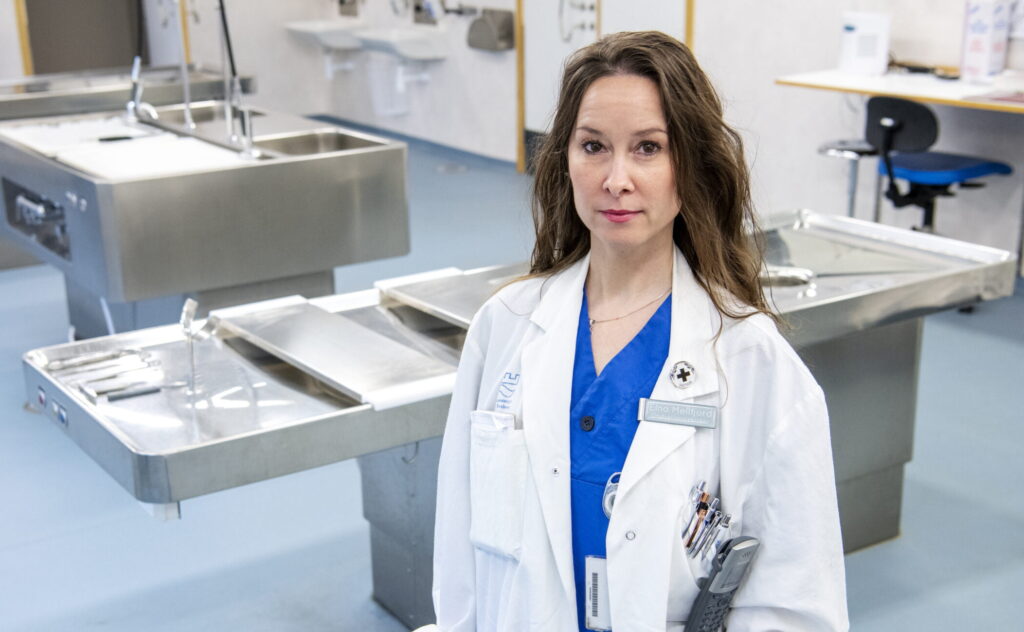 Obduktionstekniker Elna Mellfjord står framför en rostfri bänk i obduktionssalen.