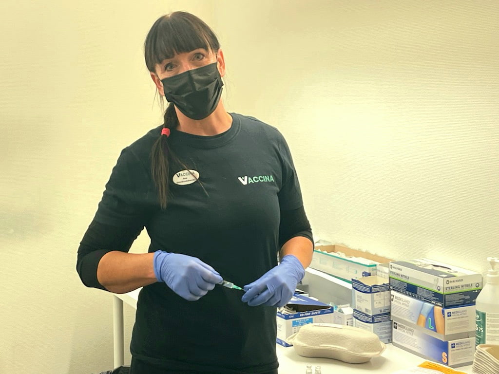 Ana Cagnais, distrikts- och IVA sköterska och platsansvarig för verksamheten hos Vaccina i Skövde står utrustad för vaccination med en vaccinationsspruta i handen iförd munskydd och handskar.