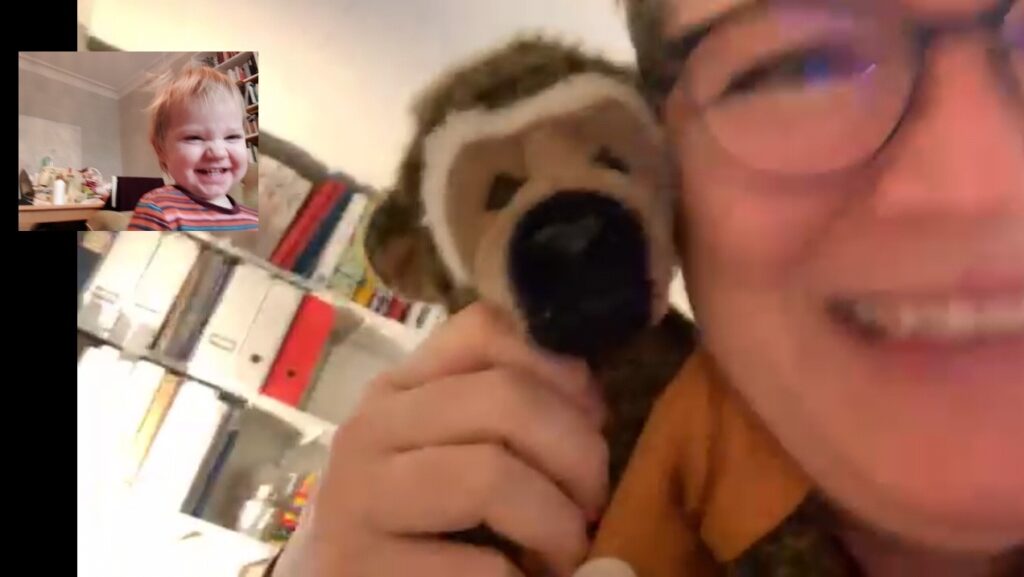 En kvinna som leker titt ut med sitt barnbarn via video.