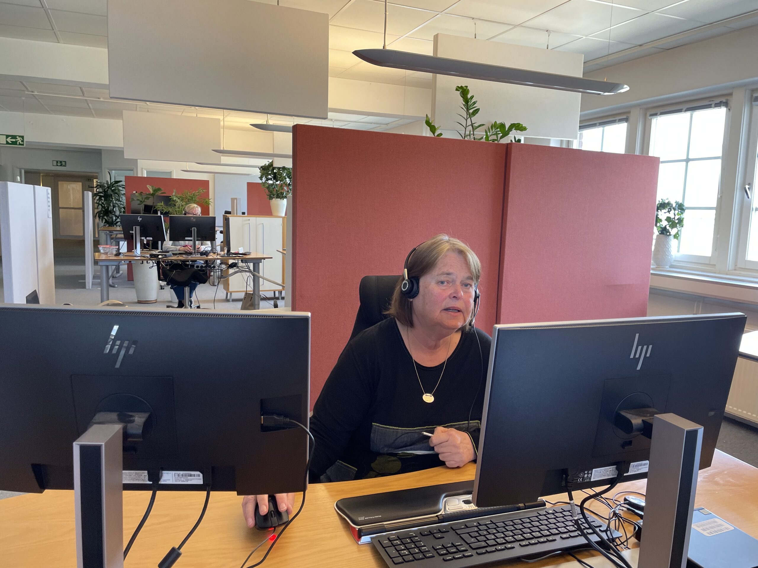 Eva-Lena Rosenqvist med lurar på öronen sitter framför sin datorutrustning och svarar i telefon på 1177.