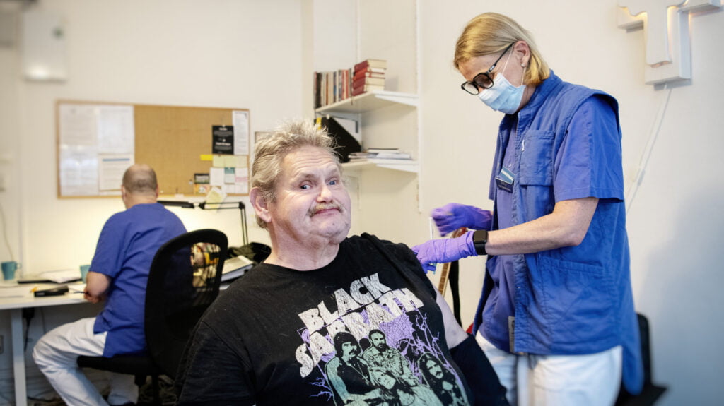 SU-teamet covid-vaccinerar på Räddningsmissionens frukostcafé. Anna Biveby-Nilsson, sjuksköterska, vaccinerar Jan Olsson. Foto: Anna Rehnberg.