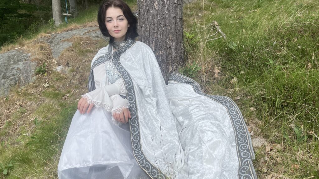 Silje Lunde sitter under ett träd i skogen i sin Isowyndräkt.