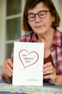 Gunvor håller upp den egna boken "mitt hjärta är ditt".