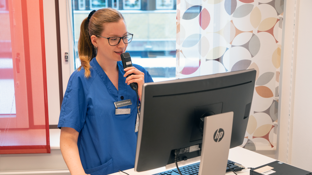 En person står vid en datorskärm och talar in i en mikrofon